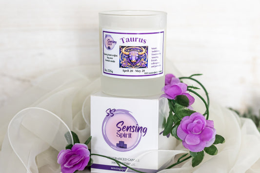 Candle and packaging with 'Sensing Spirit' branding and purple flowers on a white background